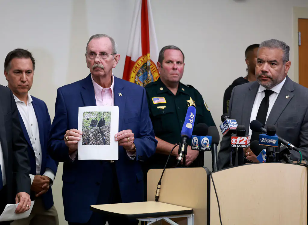 Palm Beach County Sheriff Ric Bradshaw holds a photograph of the rifle and other items found near where a suspect was spotted. Credit: Joe Raedle / Getty