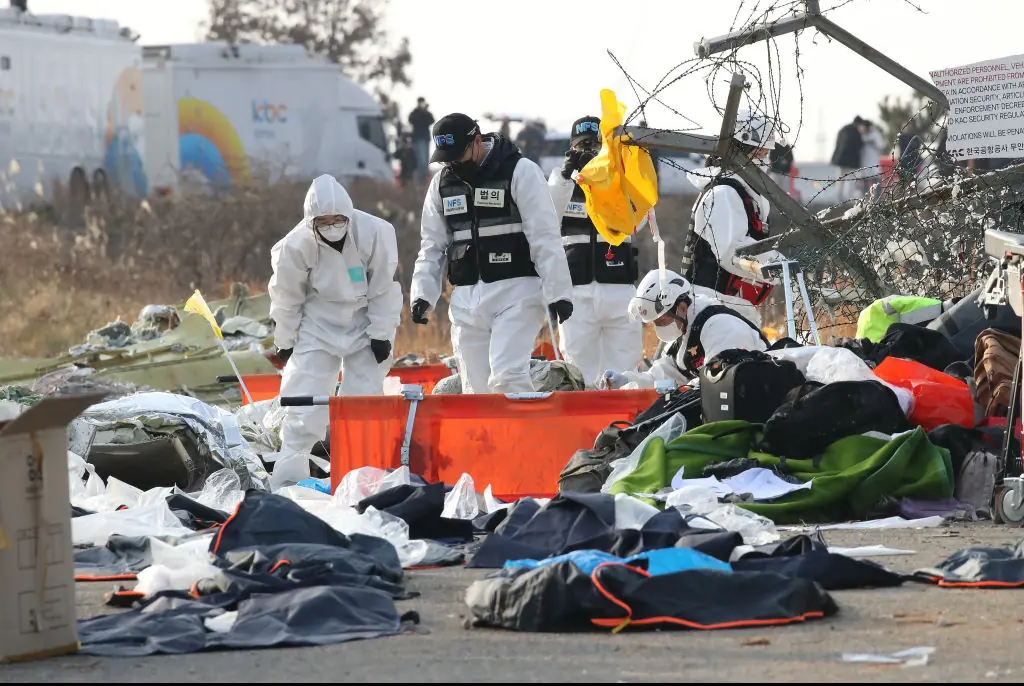 South Korean rescue team members check near the wreckage of a passenger plane at Muan International Airport. Credit: Chung Sung-Jun/Getty