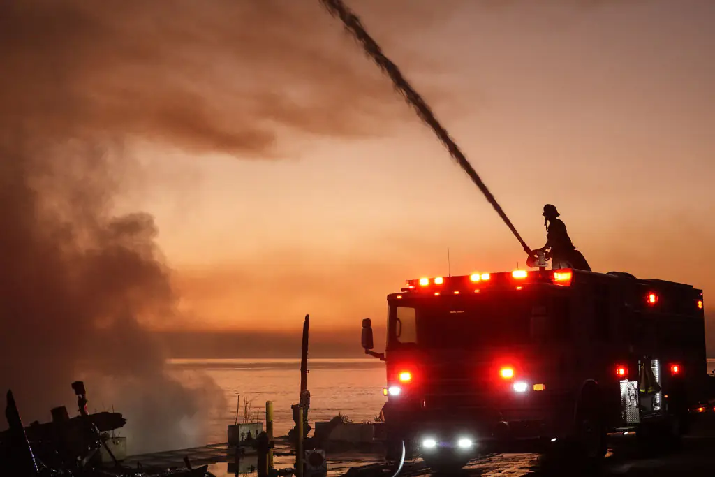 Firefighters spray water to combat flames at sunset in Pacific Palisades, California. Credit: NurPhoto / Getty