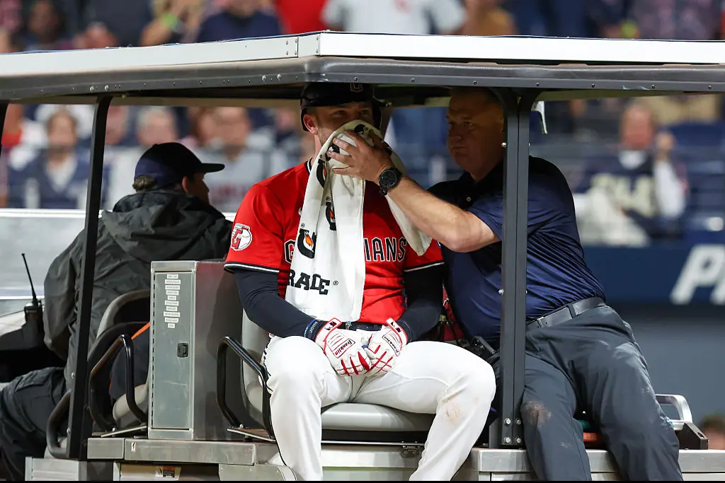 Cleveland Guardians Head Athletic Trainer holds a towel to the face of Cleveland Guardians designated hitter David Fry. Credit: Icon Sportswire / Getty
