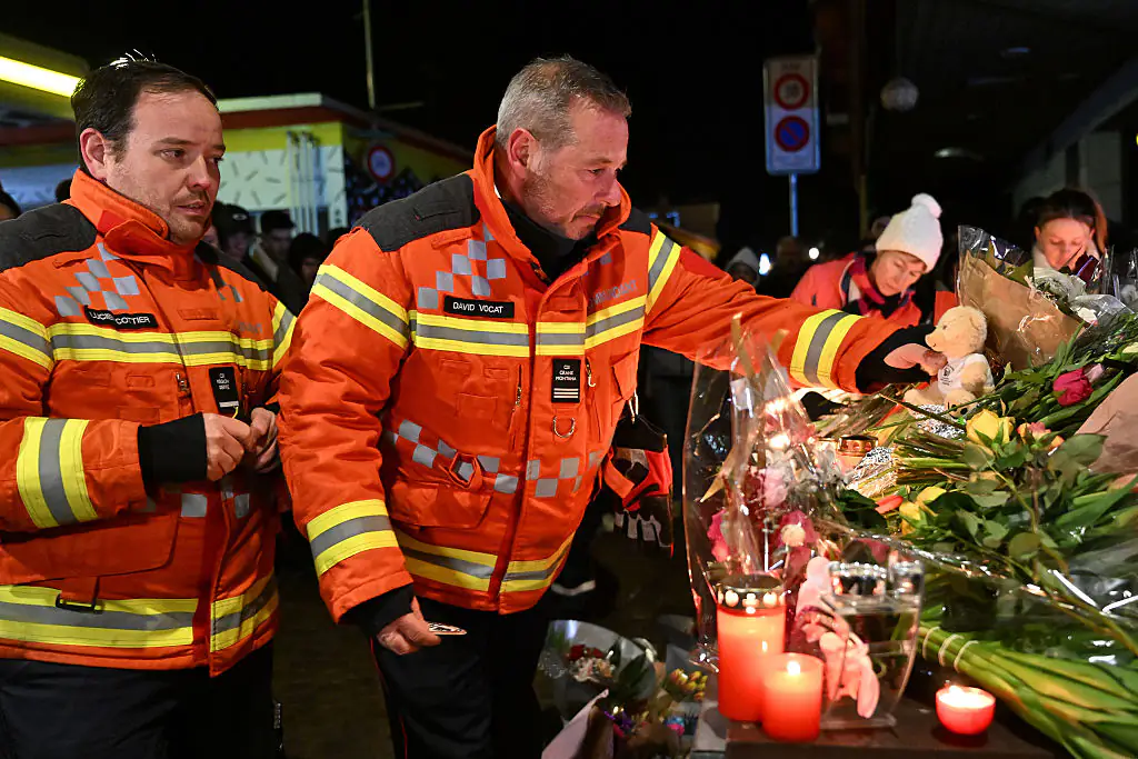 Firefighters gather to leave flowers and candles at the scene after a fire broke out overnight at Le Constellation bar on January 01, 2026