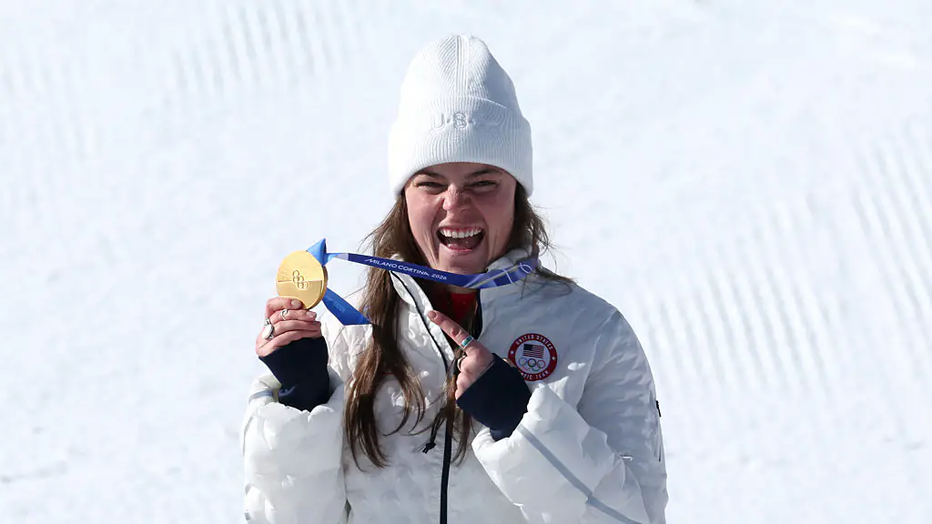 CORTINA D'AMPEZZO, ITALY - FEBRUARY 08: Gold medalist Breezy Johnson of Team United States celebrates on the podium during the medal ceremony for the Women's Downhill on day two of the Milano Cortina 2026 Winter Olympics at Tofane Alpine Skiing Centre on February 08, 2026 in Cortina d'Ampezzo, Italy. (Photo by Al Bello/Getty Images)
