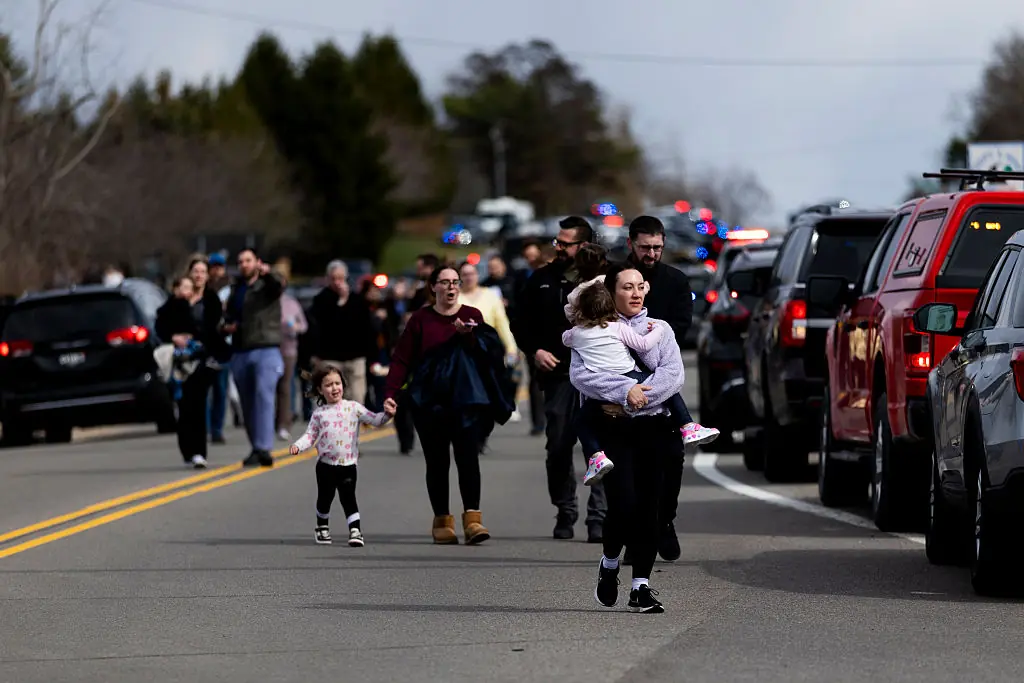 Law enforcement escorts families and their children to their cars after the attack. Credit: Emily Elconin / Getty