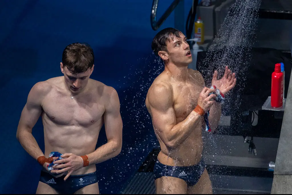 om Daley rinses in the shower with Matty Lee of Great Britain after their final dive during their gold medal performance in the Men's Synchronised 10m Platform Diving at the Tokyo Aquatic Centre at the Tokyo 2020 Summer Olympic Games. Credit: Tim Clayton - Corbis / Getty