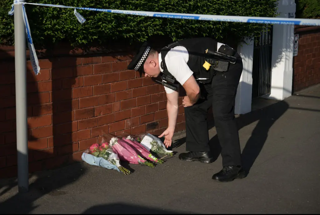 An officer lays tributes. Credit: Christopher Furlong / Getty