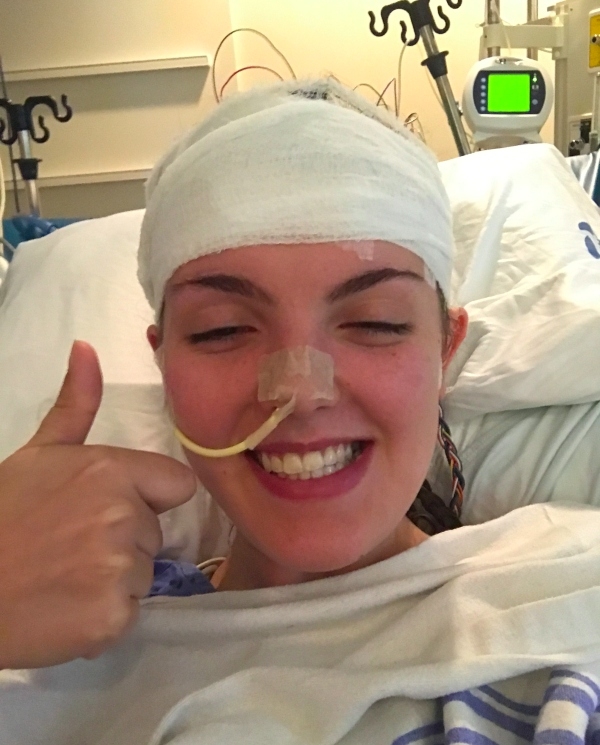 A woman smiling with a bandage around her head.