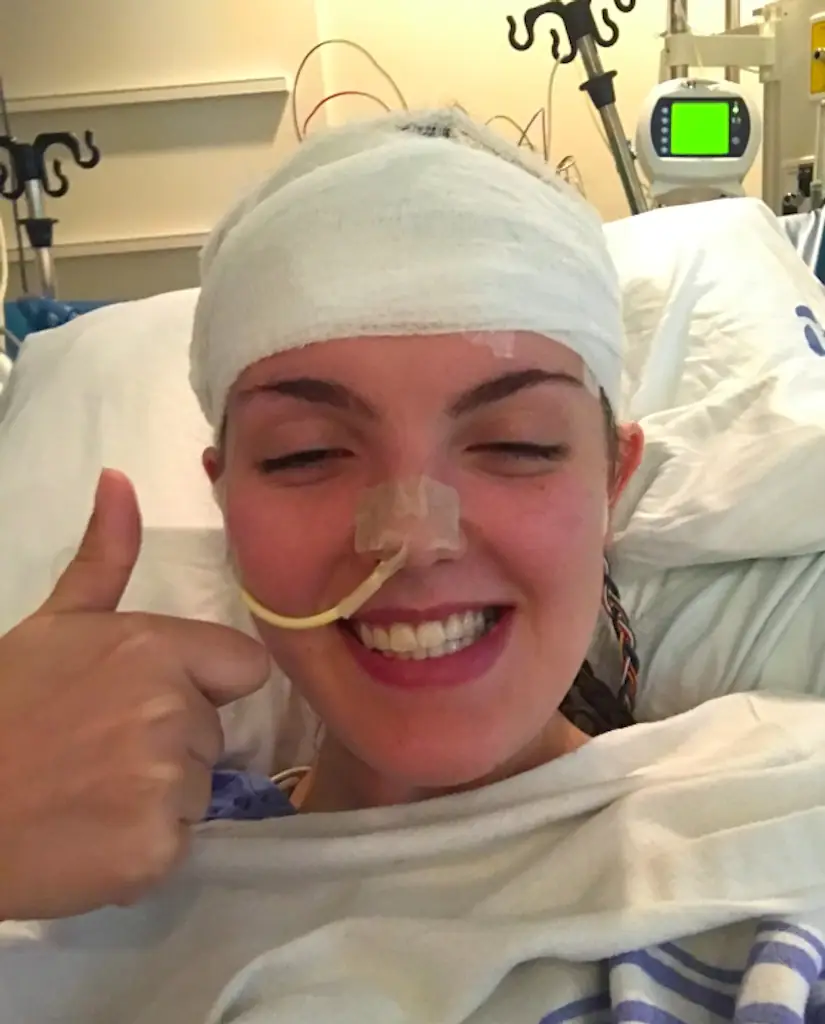 A woman smiling with a bandage around her head. 