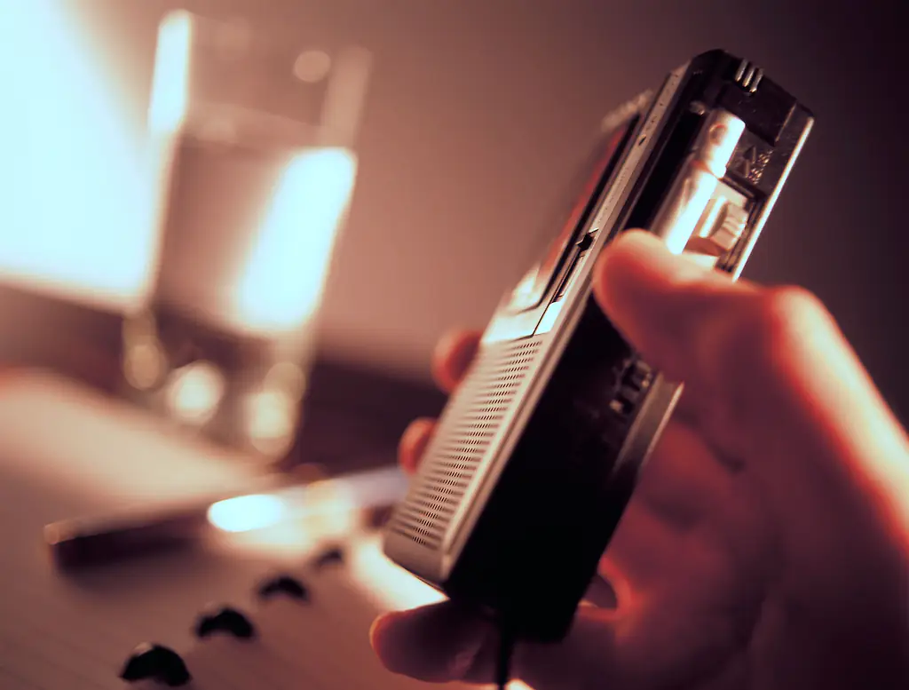 A man holds a tape recorder in an interview room