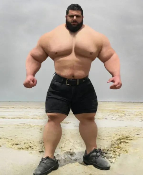 The Iranian Hulk standing on a sandy beach. 