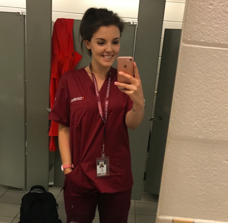 A woman taking a selfie in nurse's scrubs.