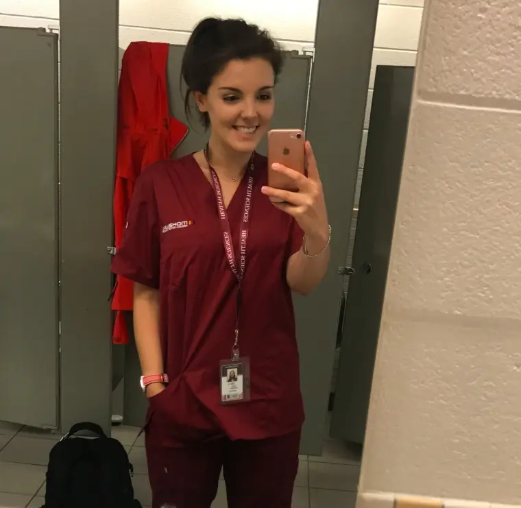 A woman taking a selfie in nurse's scrubs. 
