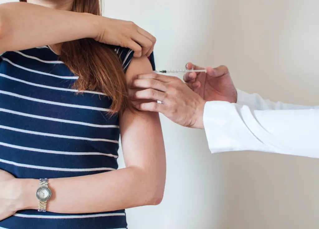 A doctor giving a woman a vaccine.