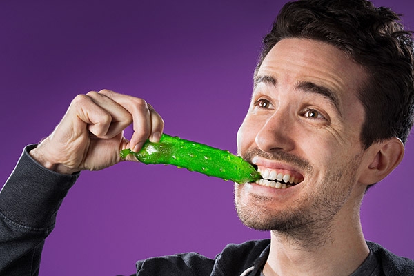 A man eating a gummy pickle.