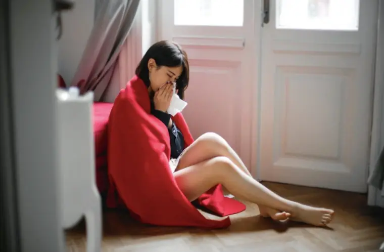 A woman sneezing into a tissue.