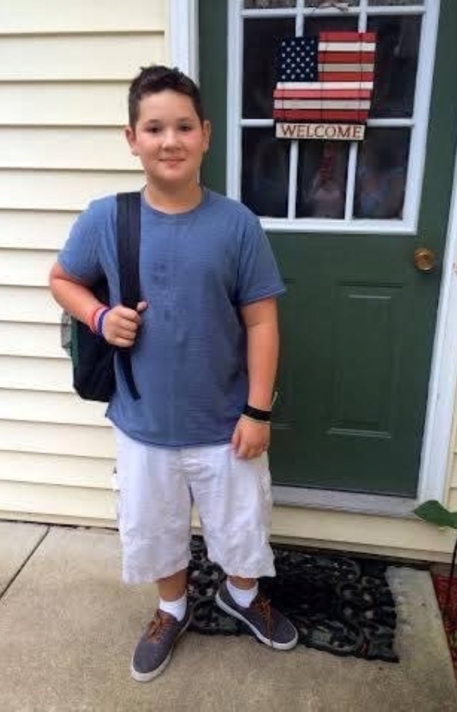 A boy standing outside his front door.