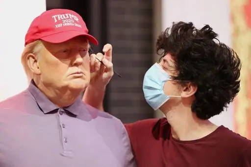 A member of the Madame Tussauds studios team adjusts a wax figure of Donald Trump which has been re-dressed in golf wear following the 2020 US presidential election, after Joe Biden's third bid for the White House has been a success as he is set to become the 46th President of the United States.