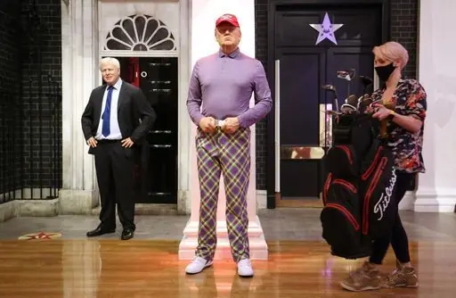 A member of the Madame Tussauds studios team places a set of golf clubs next to a wax figure of Donald Trump which has been re-dressed in golf wear following the 2020 US presidential election, after Joe Biden's third bid for the White House has been a success as he is set to become the 46th President of the United States.