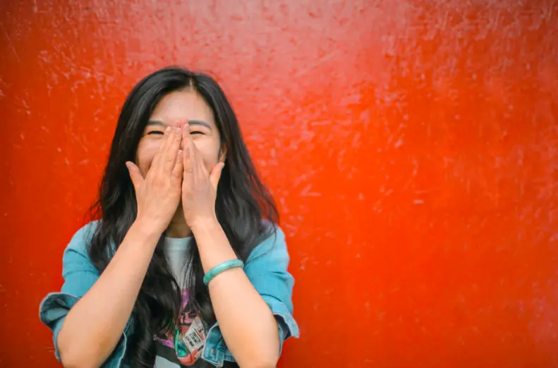 A woman covering her face to laugh.