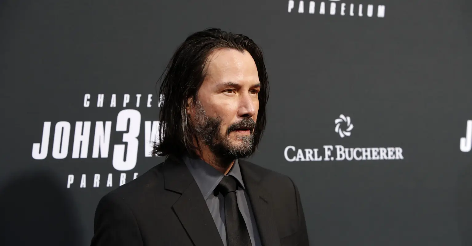 Keanu Reeves kneels on stage as adoring fans refuse to stop standing ovation