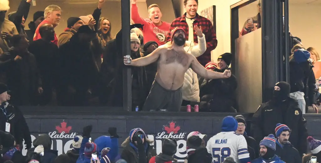 A shirtless Jason Kelce holds young fan up high so she can meet Taylor Swift