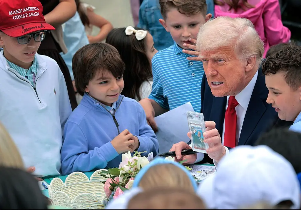 Trump shows a group of children a trading card of him raising a fist moments after surviving an attack on his life. Credit: Chip Somodevilla/Getty Imagesn 