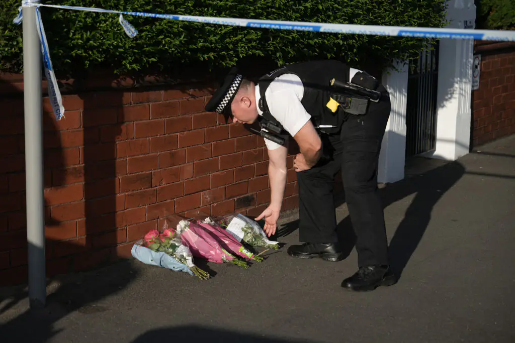 An officer lays tributes. Credit: Christopher Furlong / Getty