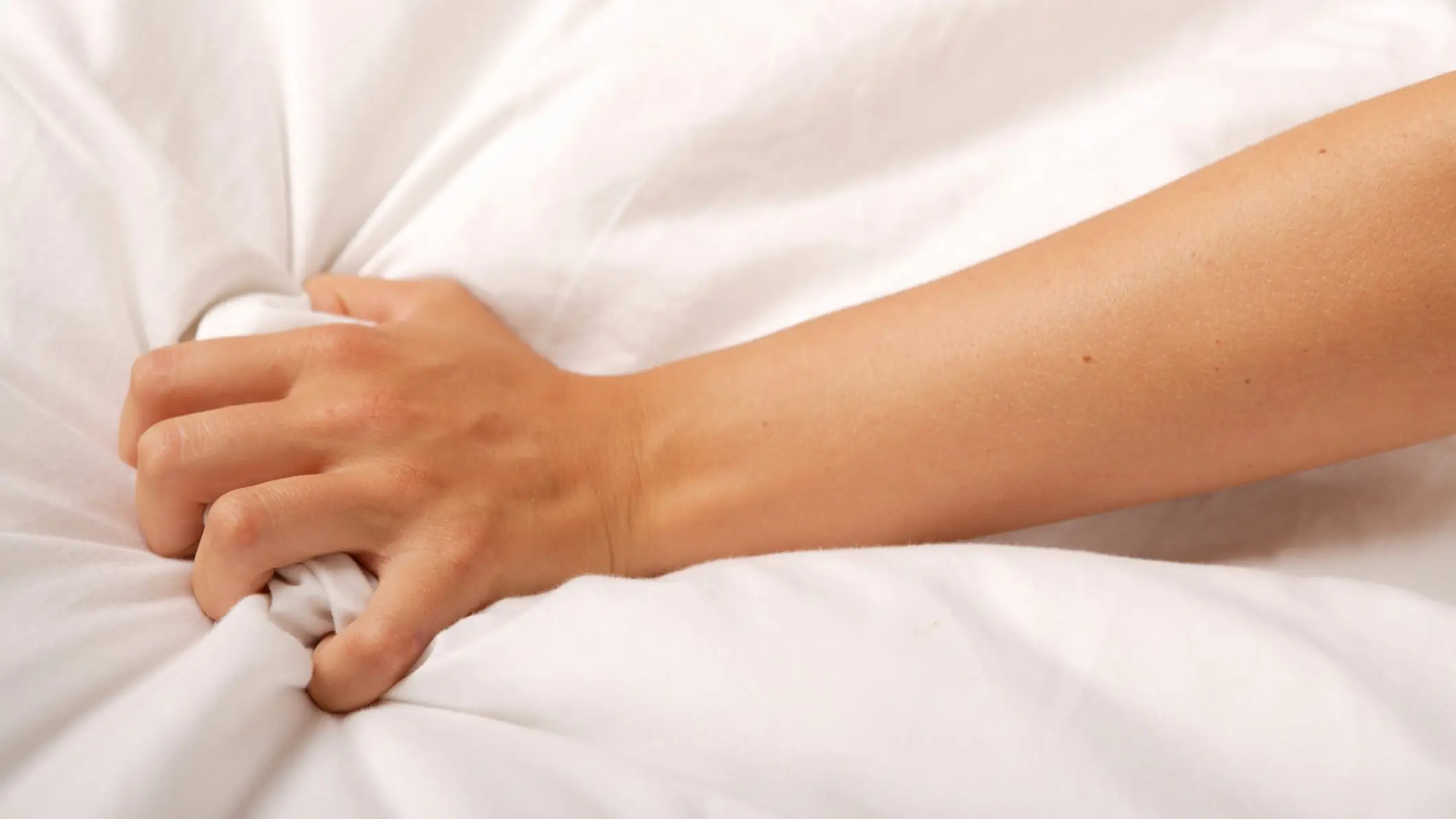 A hand grasping white sheets