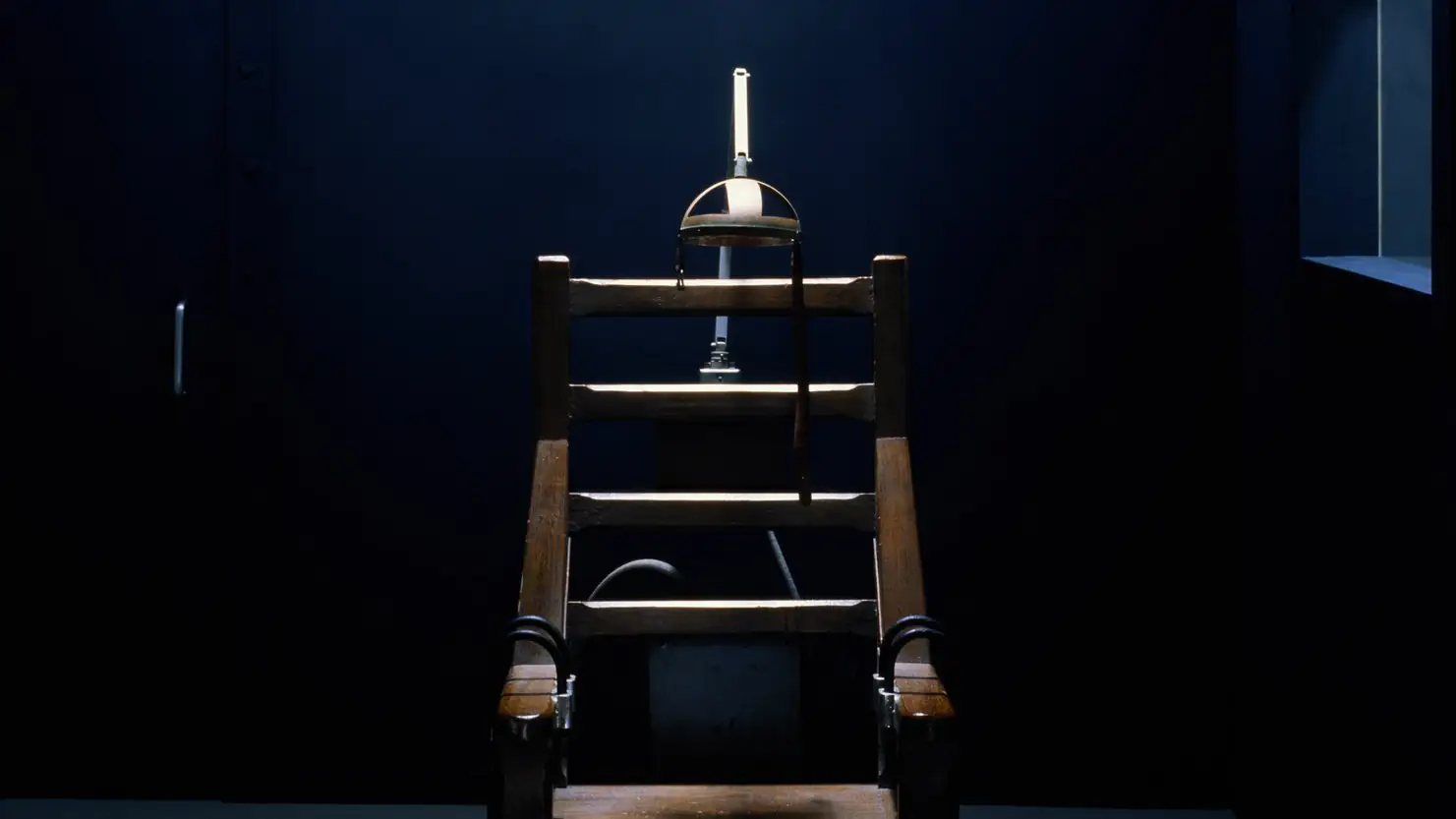 A dimly lit room with an electric chair in the middle.
