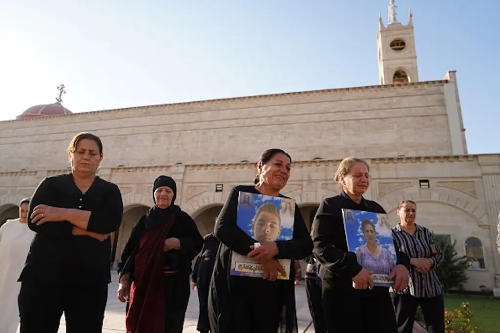 Qaraqosh fire victims' families hold pictures of them at memorial ceremony. Credit: Ismael Adnan Yaqoob/Anadolu Agency via Getty Images